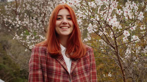 Redhaired Girl Smiling Under Spring Flower Tree