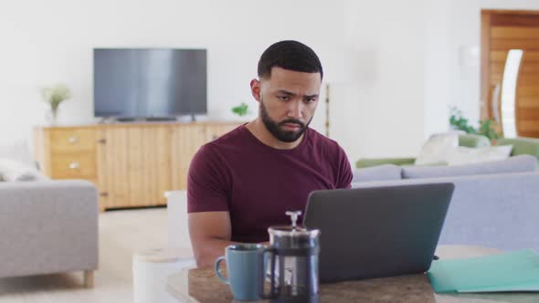 Man talking on smartphone while using laptop at home