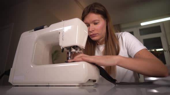  Woman Sews a Protective Mask on a Sewing Machine. Woman Works in an Apartment.