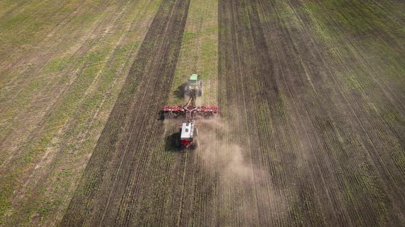 Tractor plowing and fertilizing the agricultural fields in the springtime