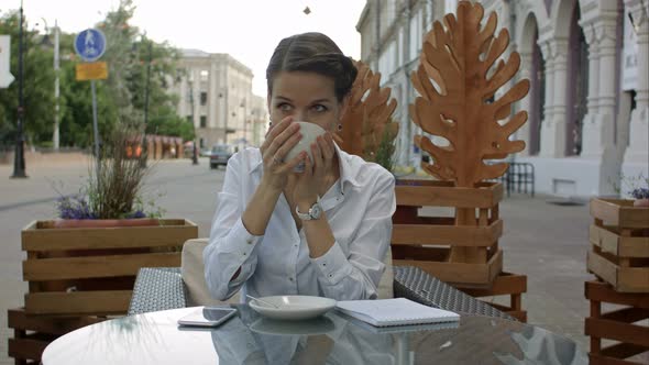 Happy Pensive Woman Drinking in a Coffee Shop Terrace in the Street