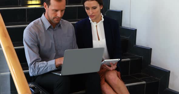 Business colleagues working on laptop and digital tablet in stairs 4k