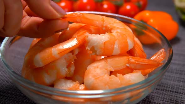 A Female Hand Lays a Delicious Shrimp in a Glass Bowl 