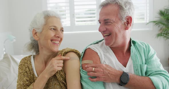 Happy caucasian senior couple showing plasters after vaccination