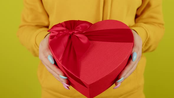 Body Part of Woman with Red Gift Box in Form of Heart on Yellow Background