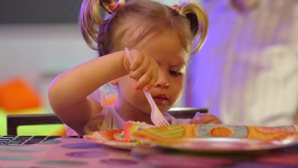 Cute Little Girl Eating a Piece of Cake on a Paper Plate with a Plastic Fork