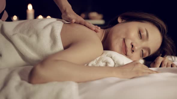 beautiful woman is relaxed by a dark oil massage in the spa