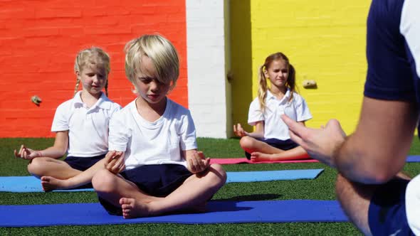 Yoga instructor instructing children in performing yoga