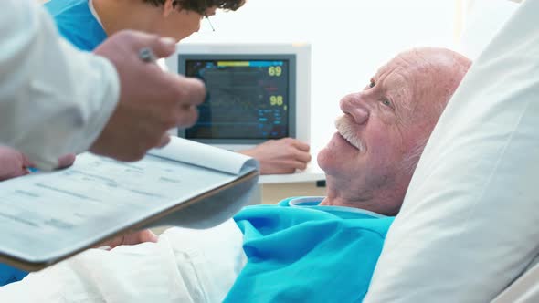 Man laying on hospital bed and answering doctor's question