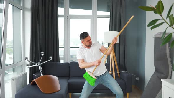 Man Does the Cleaning and Imagines Himself a Rock Star Plays the Broom Like a Guitar