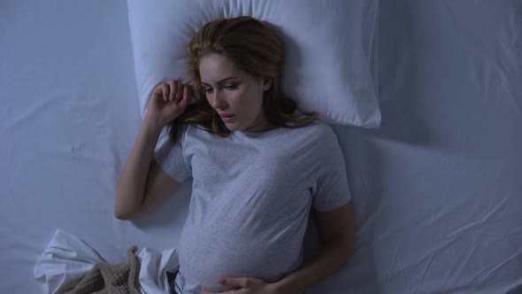 Female Expectant Lying in Bed Feeling Nausea, Morning Sickness, Pregnancy Health