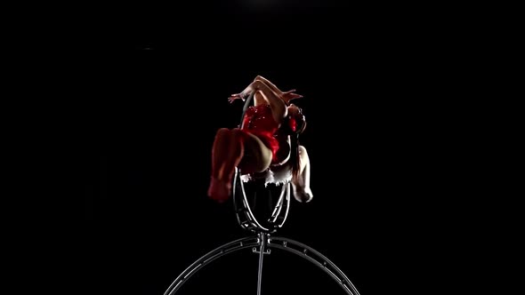 Aerial Gymnasts Performs a Trick on the Hoop Metal Construction. Black Background. Slow Motion