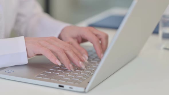 Hands of Old Female Doctor Typing on Laptop