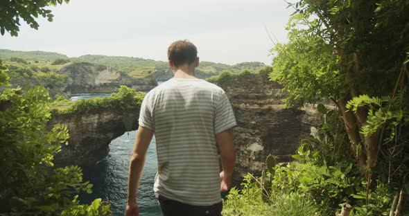 Dolly Shot Following a Male Tourist Walking Towards the Stunning Arch and Ocean Cliffs of Broken