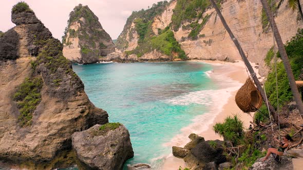 Aerial view of attractive woman swinging at Diamond Beach shore, Indonesia.