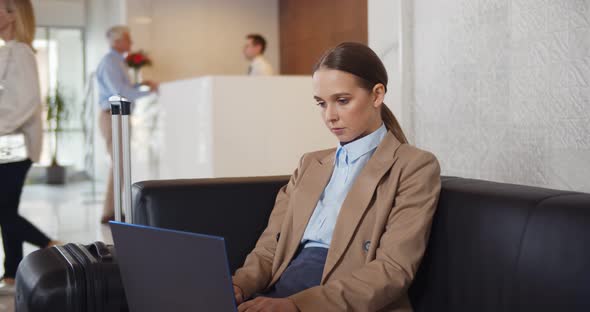 Beautiful Young Business Woman Working on Computer in Hotel Lobby