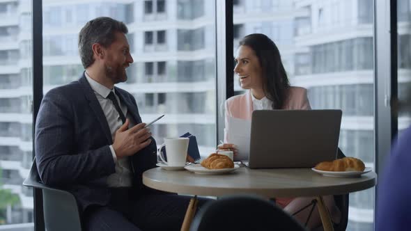 Happy Business Couple Talking Discussing Company Success Using Laptop in Cafe