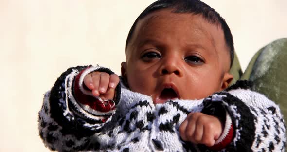 The Asian newborn baby is sitting on his mother's lap, in the winter season,