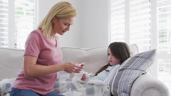 Mother measuring temperature of her sick daughter at home