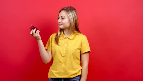 Cute and Slightly Fat Girl in a Yellow T-shirt Holds a Red Onion in Her Hand.