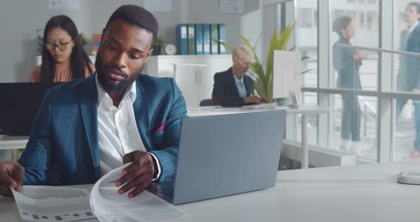 Handsome African Entrepreneur Using Laptop Sitting at Desk in Open Space Office