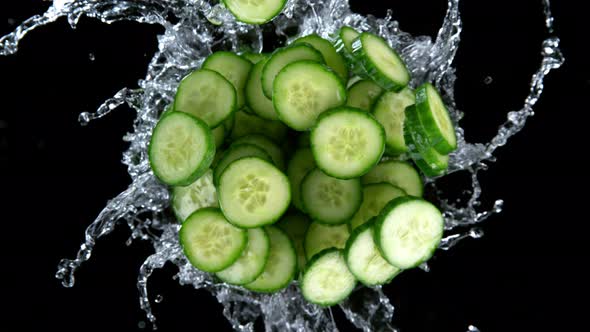 Super Slow Motion Shot of Rotating Exploded Cucumber Slices and Splashing Water on Black at 1000Fps