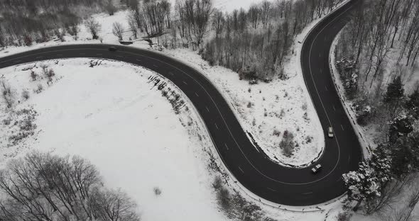 Aerial, drone shot, panning around cars on a wet, winding road