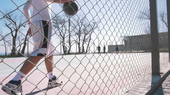 Portrait of a Basketball Player Walking on an Outdoor Basketball Court and Dribbling the Ball Slow