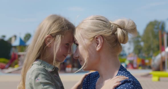 Close Up of Loving Mother Hugging and Spending Time Together with Preschool Daughter Outdoors