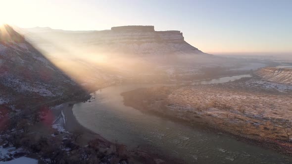 Flying over river as the sun rays shine over the desert landscape in winter