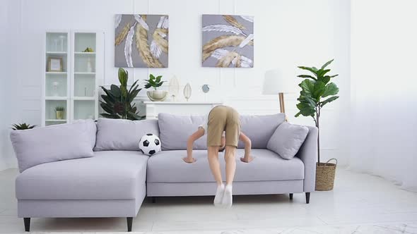 Smiling 12-Aged Boy Running Up to the Sofa in the Living Room and Making a Rack on it