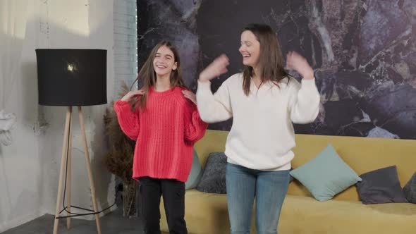 Cheerful Mother and Daughter Dancing to Favourite Song Together