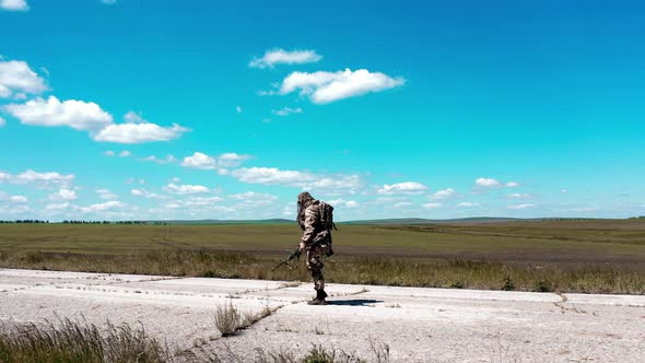 A Lone Tired Soldier Walks Along an Old Concrete Road Against a Blue Sky