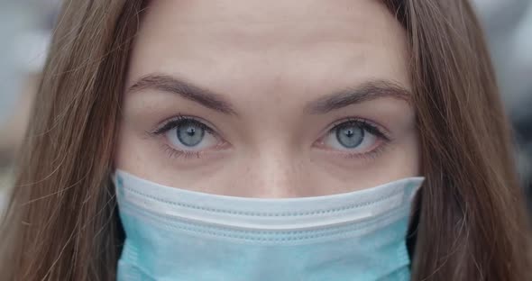 Close-up of Grey Eyes of Young Woman in Protective Mask Looking at Camera. Portrait of Brunette