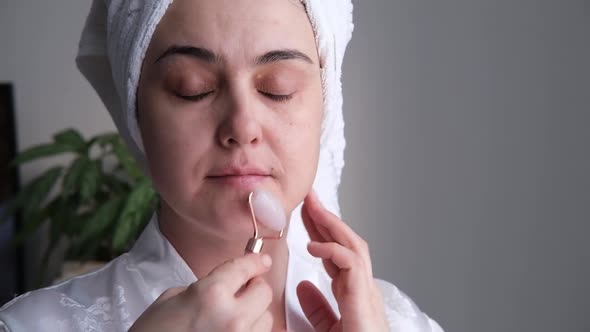 A Closeup Photo of a Young Woman Looking Relaxed and Smiling Doing a Massage with a Face Roller Made