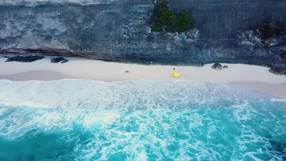 Girl on Sandy Beach Under Cliff with Azure Water