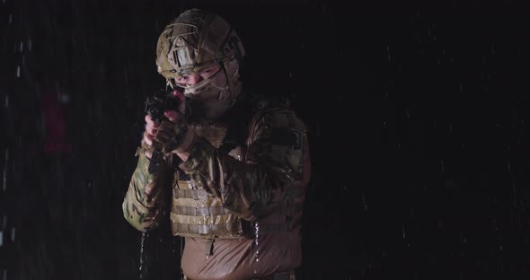 Closeup Heavy Raindrops on Soldier in Camouflage on the Night Taking Military Action Aiming Weapon