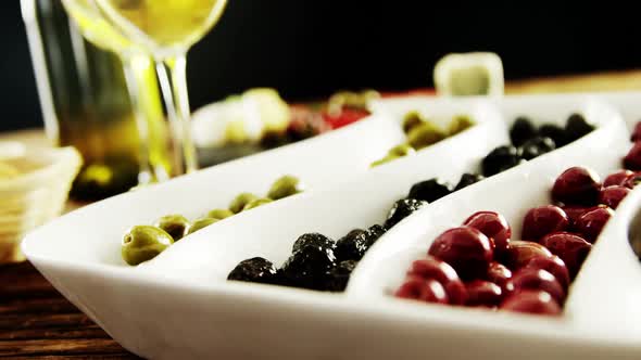 Two glasses of wine and a tray with berry fruits and olives