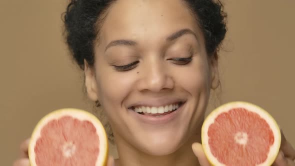 Beauty Portrait of Young African American Woman Having Fun Covering Eyes with Halves of Grapefruit