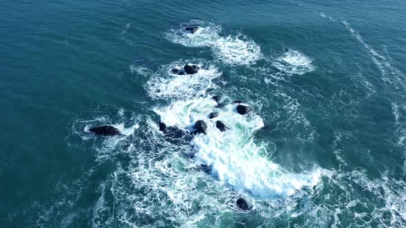 Aerial view of ocean waves splashing in rocks