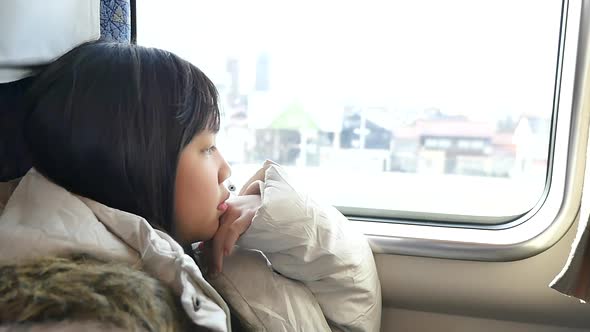 Little Asian Girl Looking Through Window. She Travels On A Train Slow Motion