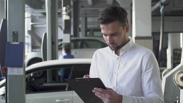 Young Handsome Man in Car Service Signed Documents About Car and Smiling on the Background of His