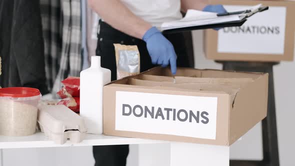 Young Volunteer Checking Clothes Donation Box and Making Notes Humanitarian Aid