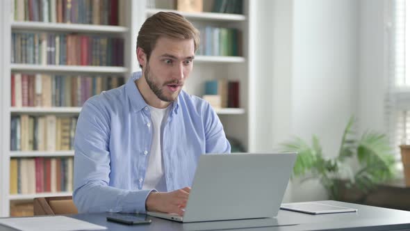 Man Feeling Shocked While Using Laptop in Office