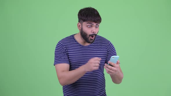 Happy Young Overweight Bearded Indian Man Using Phone and Getting Good News