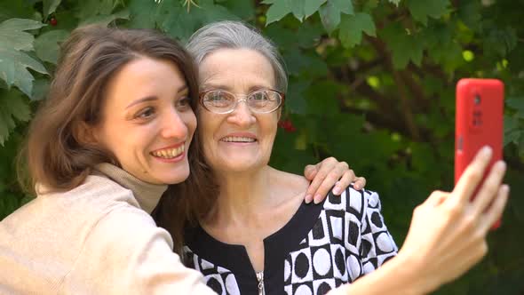 Adult Daughter and Senior Mum are Taking Selfportrait Picture Selfie on Red Smartphone Together