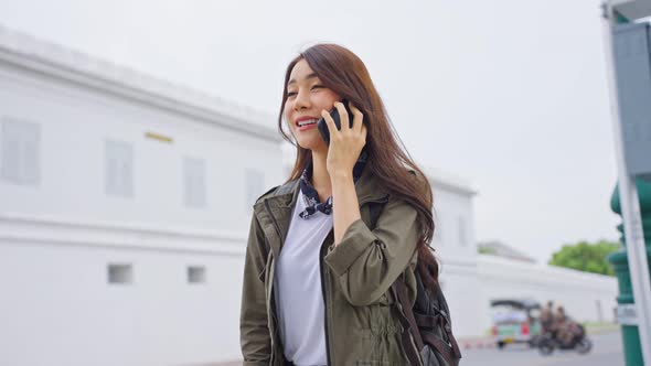 Asian attractive woman backpacker talking on phone while walk in city spend time on holiday vacation