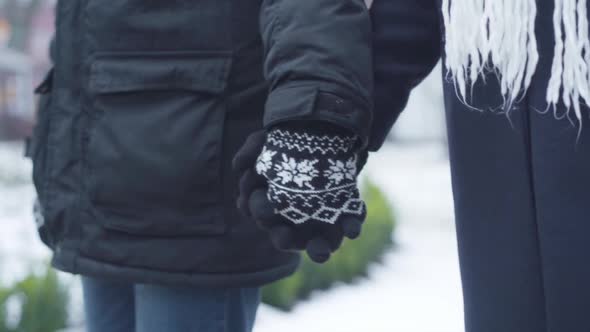 Close-up of Male and Female Hands in Winter Gloves Holding Each Other. Man and Woman Strolling
