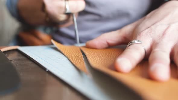 Young Man Using a Special Knife To Cut the Leather