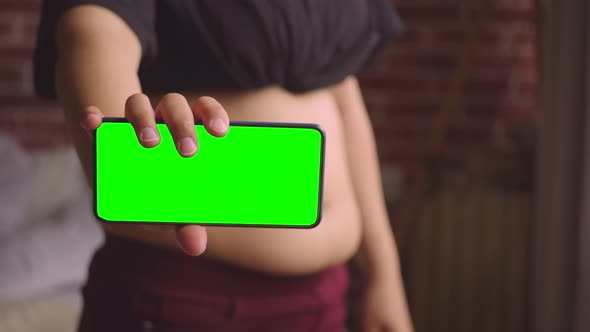 Fat Woman Stands on Huge Stomach and Shows Phone with Green Screen